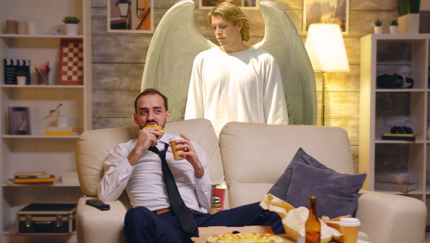 Guardian Angel Dutifully Stands Over Man Watching TV To Make Sure He Doesn’t Choke On His Pringles